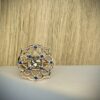 Bague Princesse en vermeil quartz fume saphirs bleus collection les pierres vue de face | 26 Passage, Créatrice de bijoux à Paris Gold floral filigree ring with blue stones around a central clear gem on a pale surface