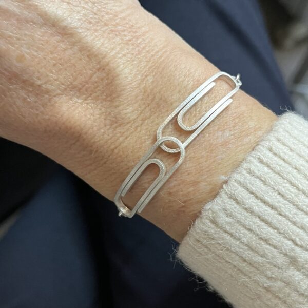 bracelet double trombone argent porte | 26 Passage, Créatrice de bijoux à Paris Silver geometric bracelet with connected rectangular links on a wrist, close-up view.