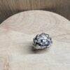 bague tressee argent vue dessus | 26 Passage, Créatrice de bijoux à Paris Close-up of a silver woven bead/ring resting on a light wood table.
