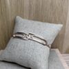 bracelet double trombone vermeil a plat sur coussin | 26 Passage, Créatrice de bijoux à Paris Rose gold bracelet with two elongated rectangular links resting on a light gray cushion.