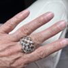 bague tressee argent vue dessus portee | 26 Passage, Créatrice de bijoux à Paris Close-up of a hand wearing a large interwoven silver ring on the finger, with light pink nails.
