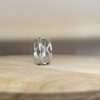 bague filaire ronde saphirs bleux collection femme vue profil | 26 Passage, Créatrice de bijoux à Paris Two silver interlaced rings with a small blue gemstone on a wooden table.