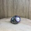 bague marie antoinette argent noir peridots ligne saphirs rose et perle eau douce creme | 26 Passage, Créatrice de bijoux à Paris Silver lattice ring with a large central pearl surrounded by a pink gemstone halo and a small green accent stone on the side.