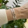 bracelet double trombone argent porte 2 | 26 Passage, Créatrice de bijoux à Paris Silver bracelet with large rectangular links on a wrist against a leafy background.