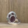 IMG_4280 | 26 Passage, Créatrice de bijoux à Paris Close-up of a silver ring with a purple gemstone and green accents on a wooden surface.