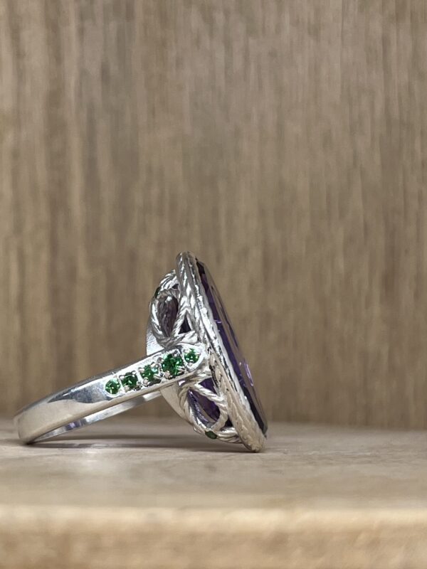IMG_4282 | 26 Passage, Créatrice de bijoux à Paris Close-up of a silver braided ring with green gemstones on a wooden surface