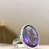 IMG_4283 | 26 Passage, Créatrice de bijoux à Paris Silver ring with a large faceted purple gem as the centerpiece, resting on a light surface.