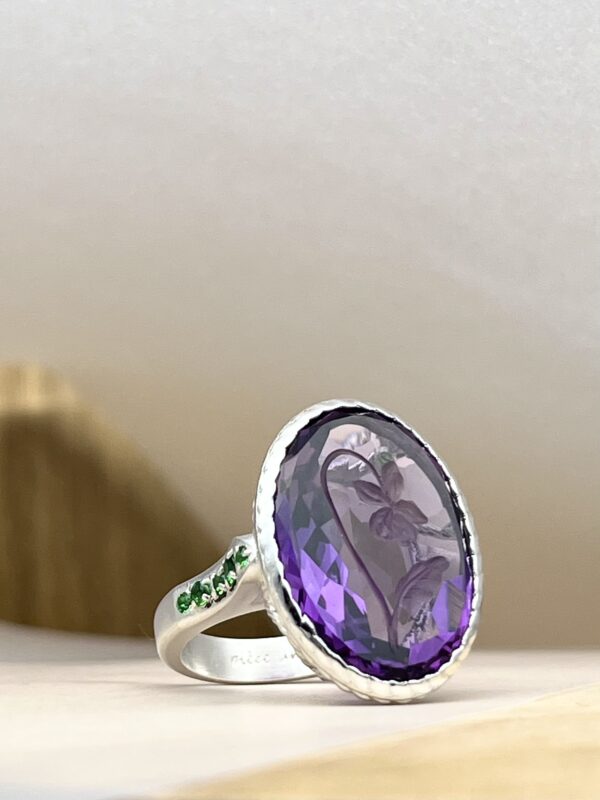 IMG_4283 | 26 Passage, Créatrice de bijoux à Paris Silver ring with a large faceted purple gem as the centerpiece, resting on a light surface.