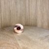 Bague twist vermeil grenat vue trois quart collection femme les pierres | 26 Passage, Créatrice de bijoux à Paris Close-up of a light brown wood floor with a pink curved object and a red gem peeking into the bottom edge of the frame.