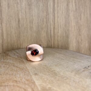Close-up of a light brown wood floor with a pink curved object and a red gem peeking into the bottom edge of the frame.