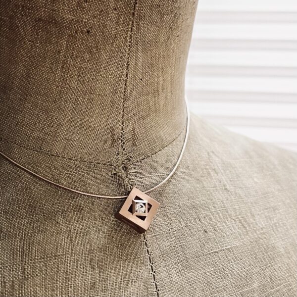 pendentif mikado vermeil zircon naturel rond sur presentoir | 26 Passage, Créatrice de bijoux à Paris Close-up of a burlap mannequin bust wearing a geometric square pendant necklace with a diamond-shaped cutout and gem centerpiece.