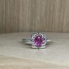 Bague mini princesse argent tourmaline rose grenats tsavorite vue de face | 26 Passage, Créatrice de bijoux à Paris Close-up of a silver ring with a large pink gemstone and green accent stones on a light wooden surface.