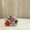 bague prairie vermeil nacre perle fleur quartz fume fleur cornaline | 26 Passage, Créatrice de bijoux à Paris Cluster ring with metal flower petals in copper and pink tones, set with small beads on a wooden surface.