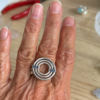 bague meringue argent saphirs bleus portee | 26 Passage, Créatrice de bijoux à Paris Close-up of a silver circular ring with blue gemstones worn on a finger.