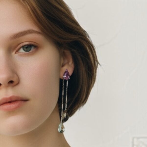 boucles tourmaline poire quartz fume cristal de roche sur argent portees | 26 Passage, Créatrice de bijoux à Paris Close-up of a woman's left face showcasing long multi-chain earrings with purple gemstone and a teardrop pendant.