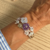 bracelet prairie pierres en argent porte | 26 Passage, Créatrice de bijoux à Paris Bracelet with translucent flower charms in purple, lavender, and clear on a wrist.