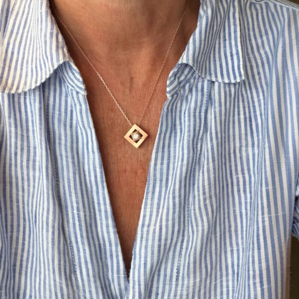 collier mikado vermeil zircon sur chaine porte | 26 Passage, Créatrice de bijoux à Paris Gold square-frame pendant with a small diamond centered on a thin chain resting on a blue-and-white striped shirt neckline